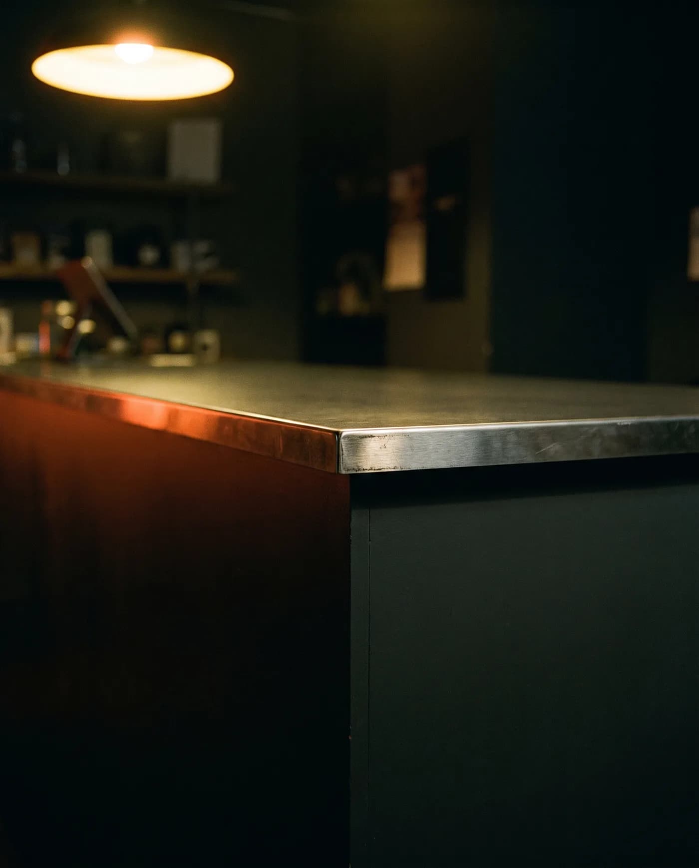 The lit edge of a dark retail counter at night, empty, shot in warm low light